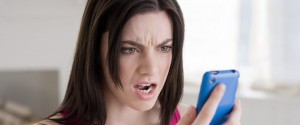 Сердитая женщина, смотрящая на мобильный телефон