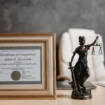 a certificate and lady justice figurine on table