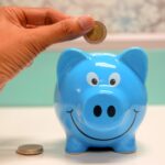 person putting coin in a piggy bank