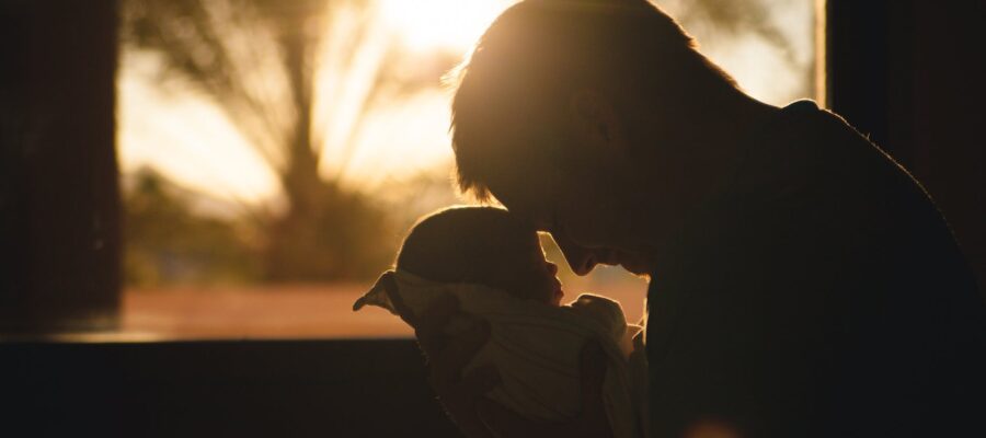 man carrying baby drawing their foreheads