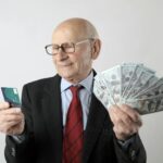 man in black suit holding banknotes and credit card