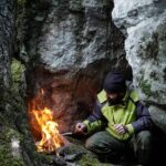 survivalist lighting campfire in mountain cave