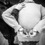 arrest scene with handcuffed individual in gray