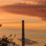sunset behind industrial chimney silhouette