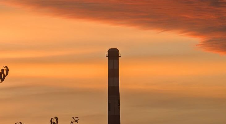 sunset behind industrial chimney silhouette