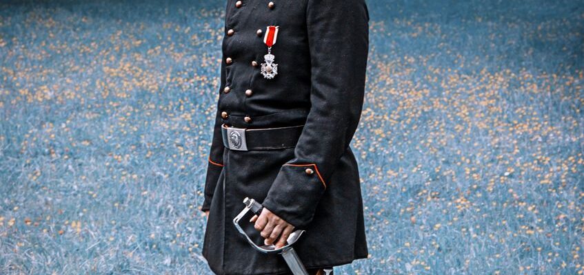man in black coat holding a sword